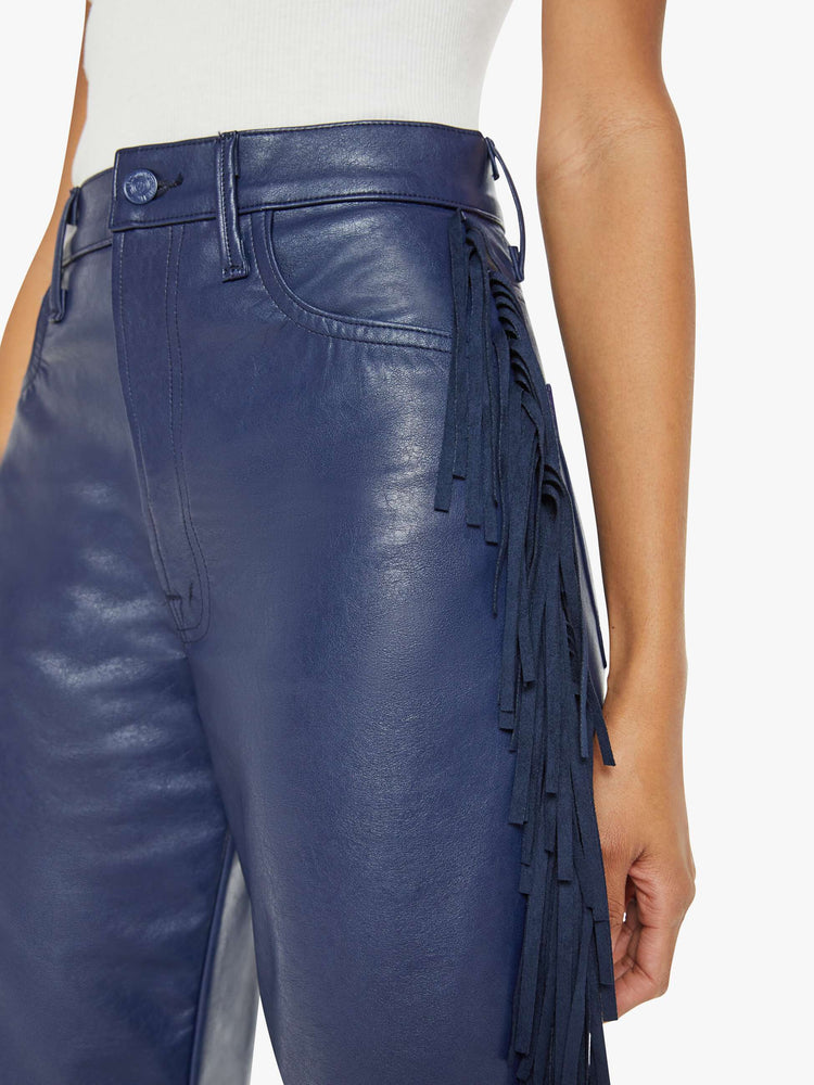 Waist close up view of a woman in a super high-waisted pant with a wide, curved leg, a 32-inch inseam and a clean hem in a navy faux leather with fringe down the leg.