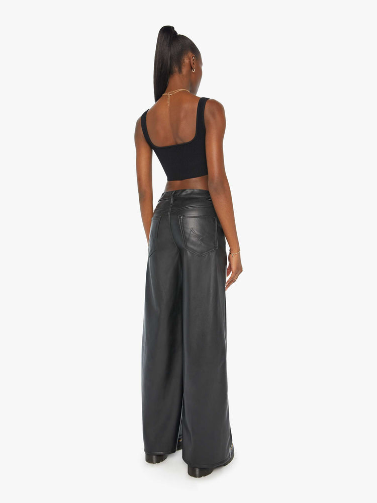 Back view of a woman black faux leather wide leg pants with a high rise, long 32-inch inseam and a clean hem.