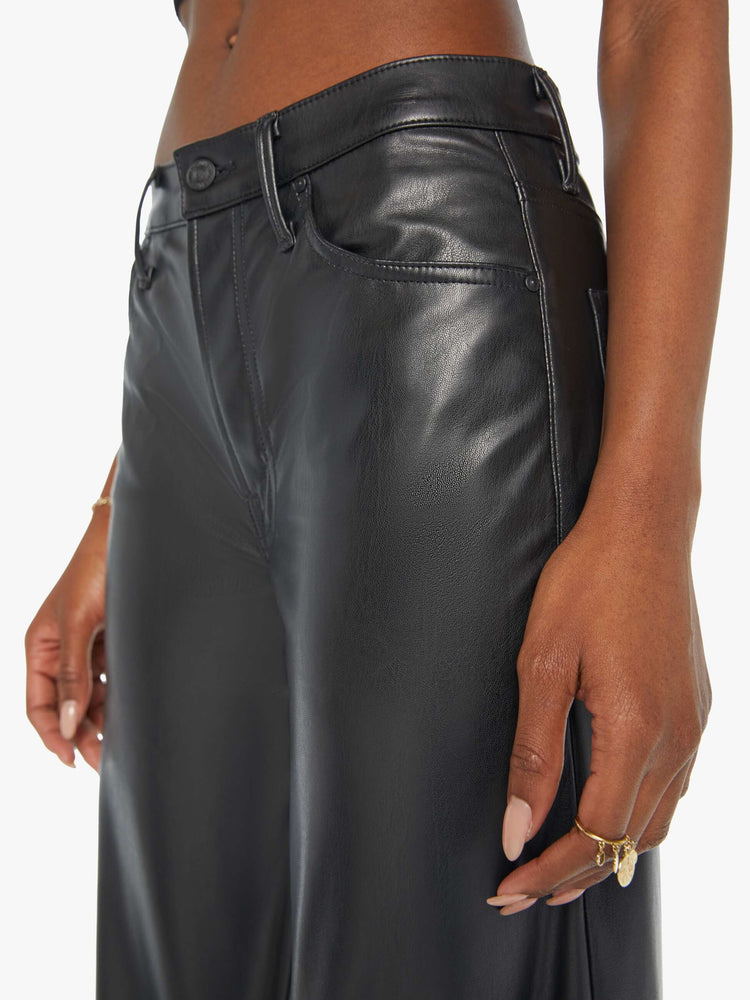 Waist close up view of a woman black faux leather wide leg pants with a high rise, long 32-inch inseam and a clean hem.