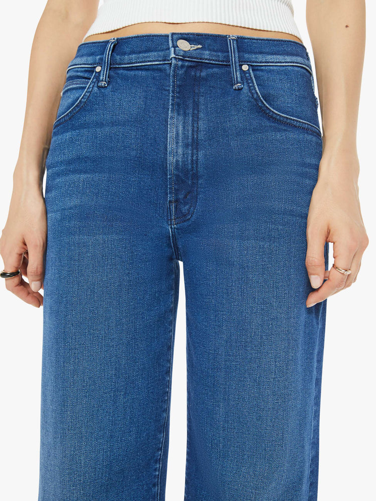 Close up view of a woman in a dark blue straight leg jean designed  to be worn loose and low at the hips with an ankle length inseam.