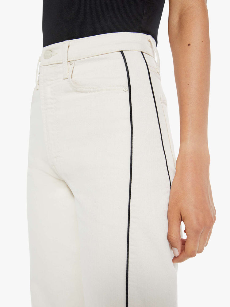 Close up view of a woman in a super high-waisted jean with a wide, curved leg, an ankle-length inseam and a clean hem in a creamy white wash.