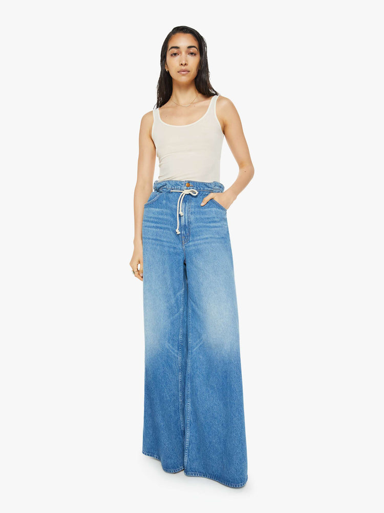 Front view of a woman in a light blue wash super high-rise jeans have a paper bag waist with a drawstring, an extra-wide, loose leg and a long 34-inch inseam with a clean hem.