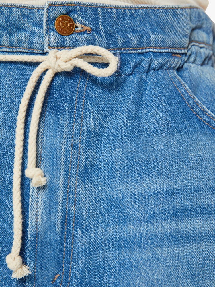 Swatch view of a woman in a light blue wash super high-rise jeans have a paper bag waist with a drawstring, an extra-wide, loose leg and a long 34-inch inseam with a clean hem.