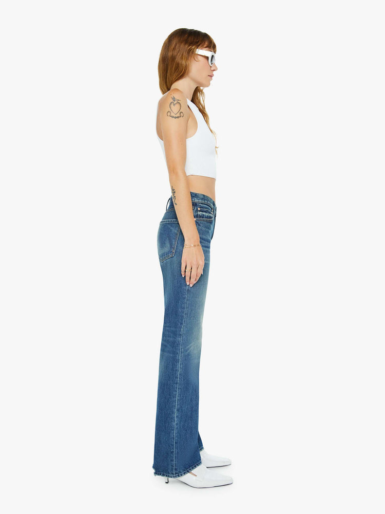 Side view of a woman in a  straight leg with a bit of a kick, the jean features a mid rise, full-length inseam and clean hem in a classic blue.