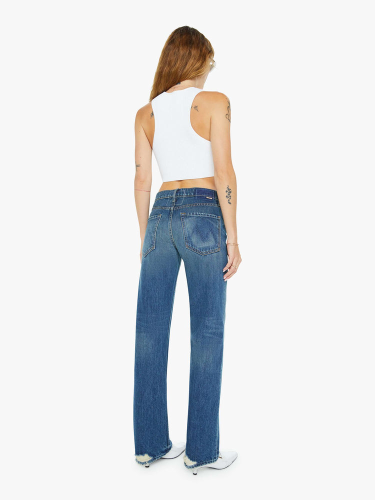 Back view of a woman in a  straight leg with a bit of a kick, the jean features a mid rise, full-length inseam and clean hem in a classic blue.