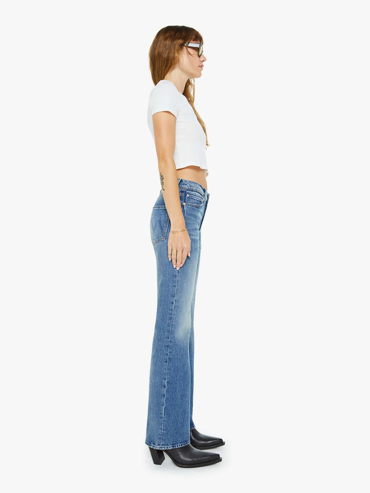 Side view of a woman in a  straight leg with a bit of a kick, the jean features a mid rise, full-length inseam and clean hem in med blue wash.