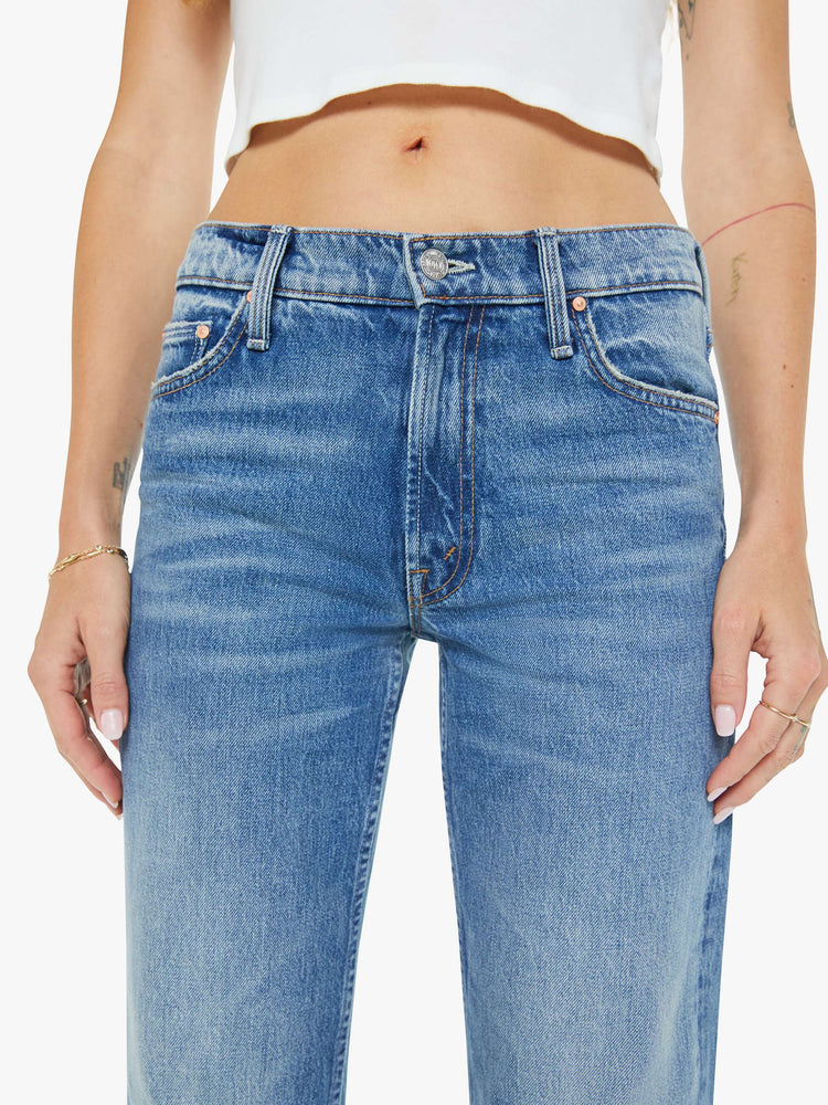 Close up view of a woman in a  straight leg with a bit of a kick, the jean features a mid rise, full-length inseam and clean hem in med blue wash.