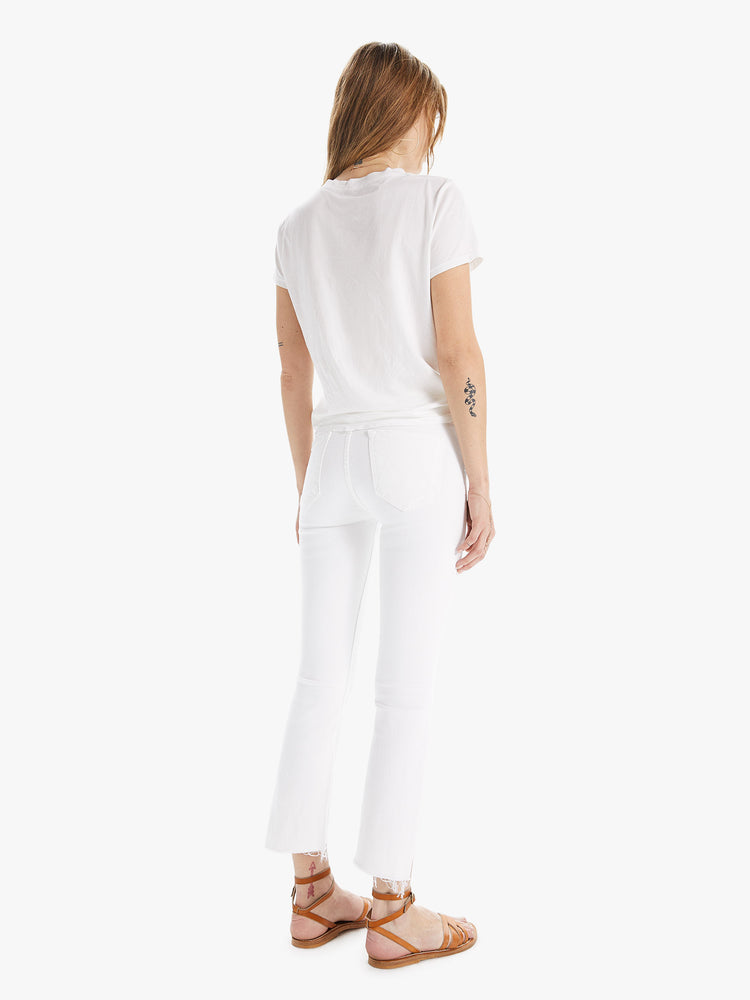 Back view of a women wearing a pair of white jeans with a step crop ankle.