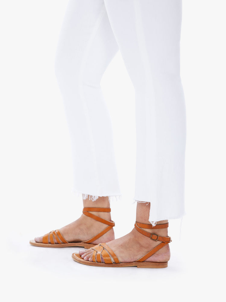 Close up view of a pair of white jeans featuring a raw step crop hem.