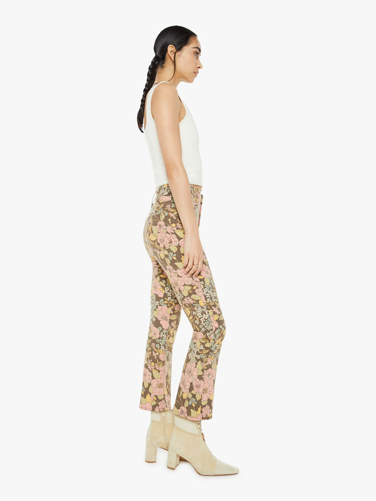 Side view of a woman in a high-rise bootcut has an ankle-length inseam and a clean hem in a floral print.