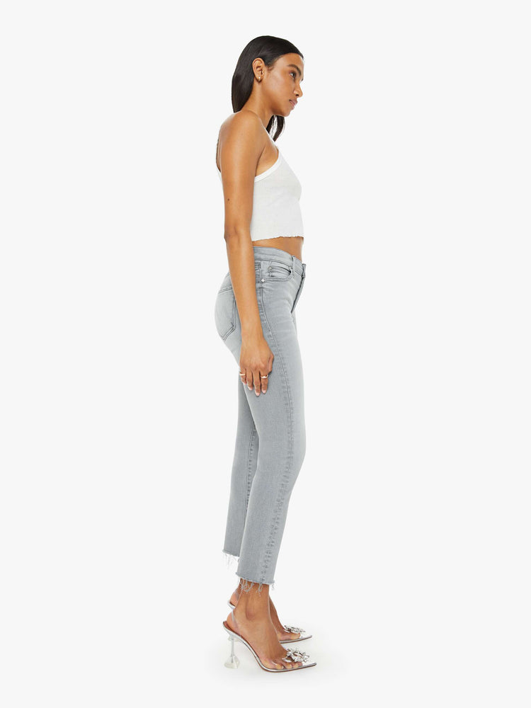 Side view of a woman in grey mid-rise straight leg with an ankle-length inseam and a frayed hem. 