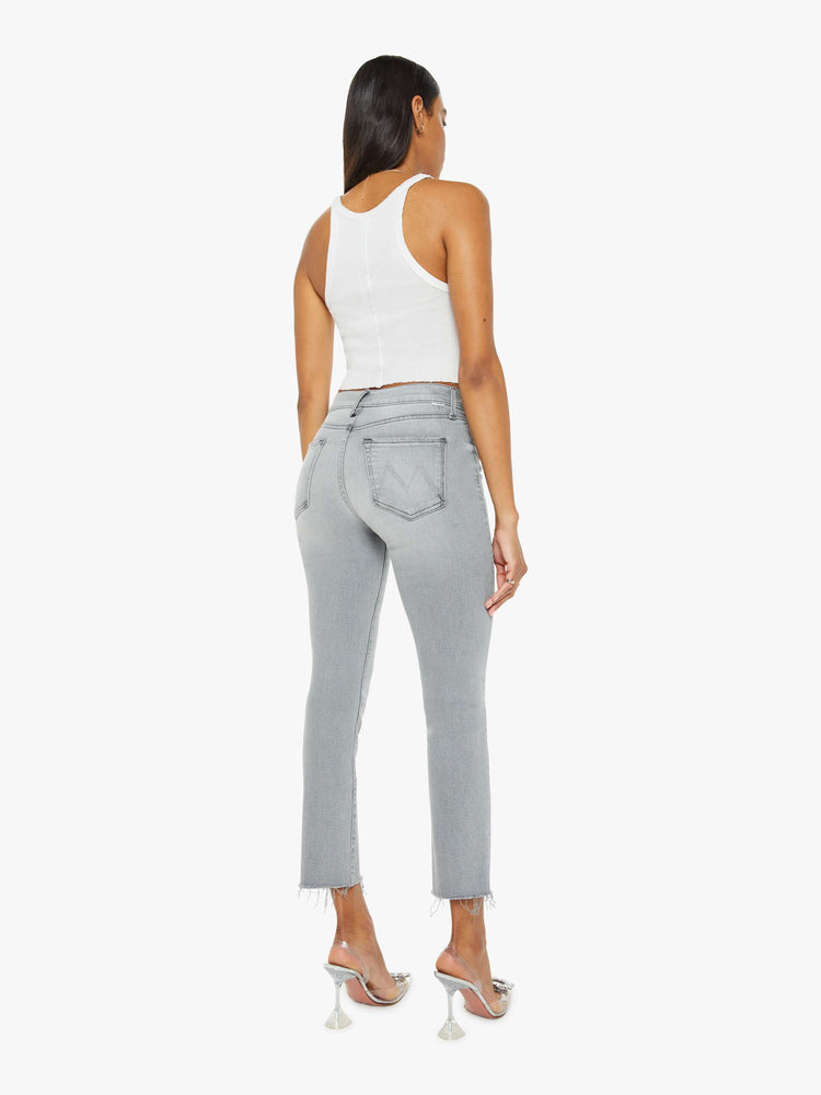 Back view of a woman in grey mid-rise straight leg with an ankle-length inseam and a frayed hem. 