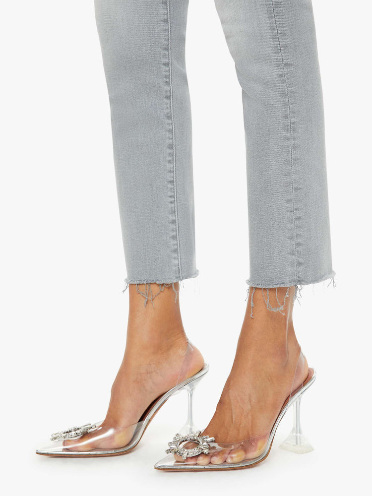 Hem view of a woman in grey mid-rise straight leg with an ankle-length inseam and a frayed hem. 