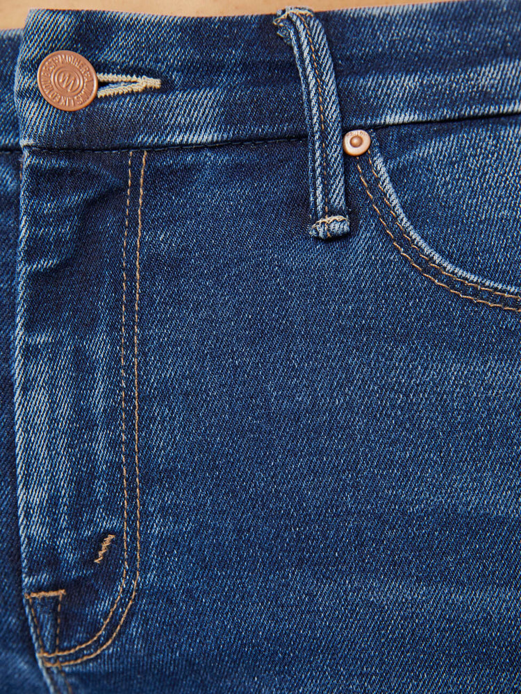 Swatch view of a woman in a dark blue mid-rise skinny jean with an ankle-length inseam and a frayed hem.