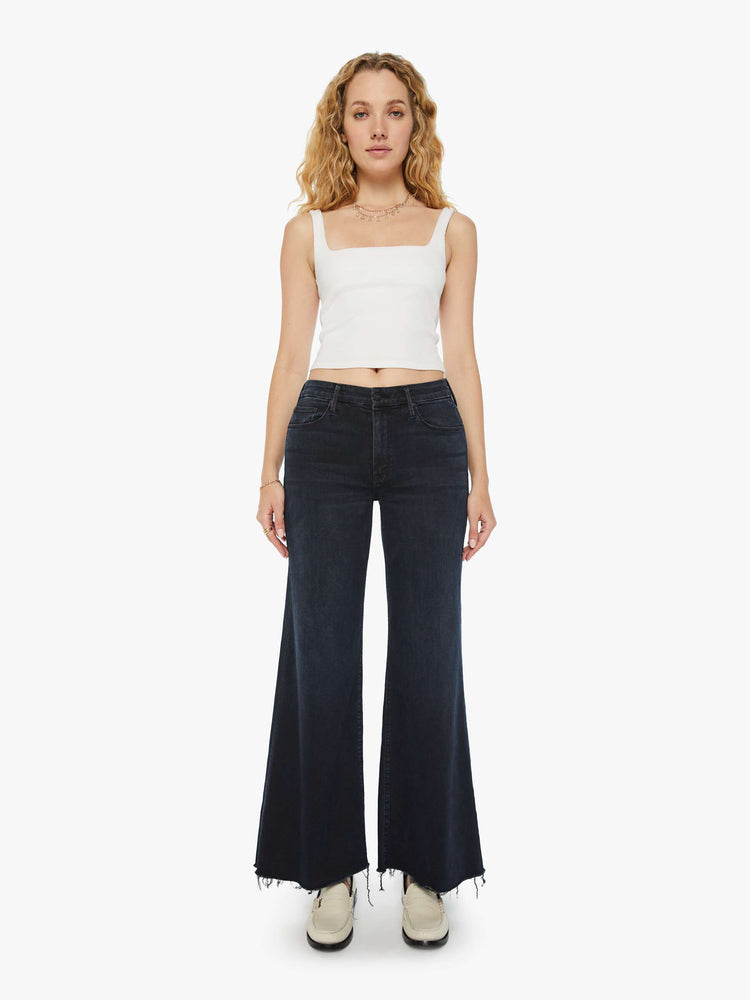 Front view of a woman in a dark denim with a high-waisted wide leg has a 31-inch inseam and a frayed hem. 