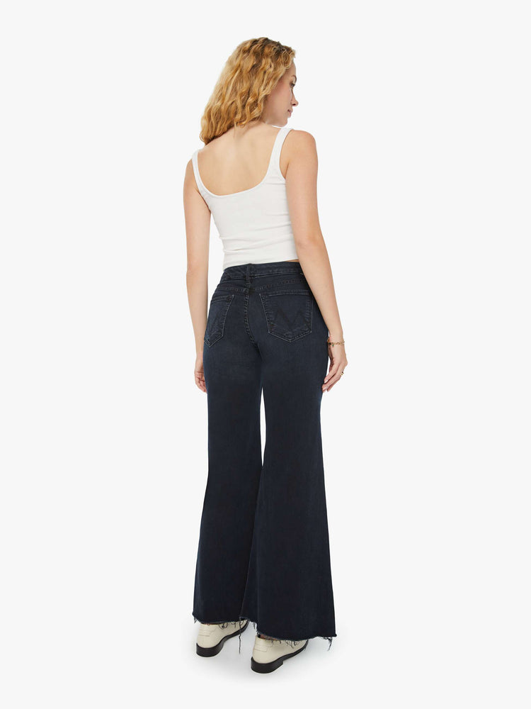 Back view of a woman in a dark denim with a high-waisted wide leg has a 31-inch inseam and a frayed hem.