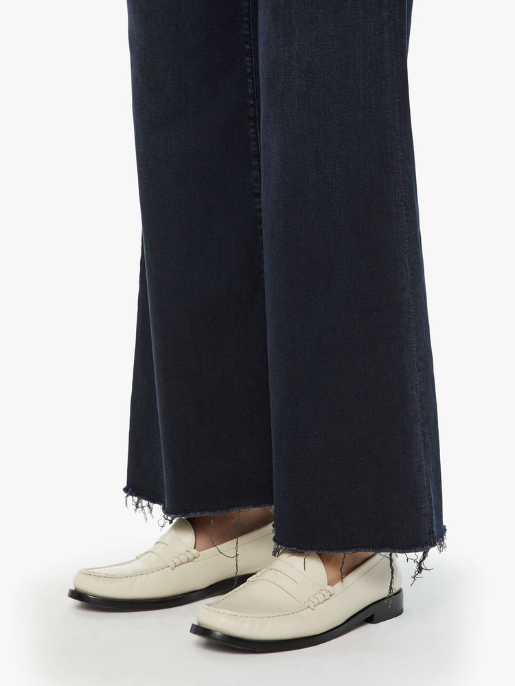 Hem view of a woman in a dark denim with a high-waisted wide leg has a 31-inch inseam and a frayed hem.