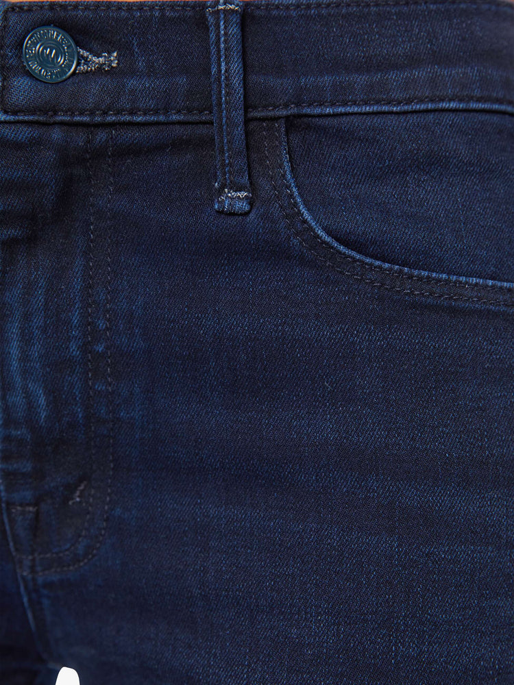 Close up view of a woman in a dark blue wash mid-rise flare with a 31-inch inseam and frayed hem.