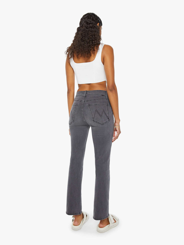 Back view of a woman in high-rise flare with a button fly and a clean ankle-length hem dark grey wash.