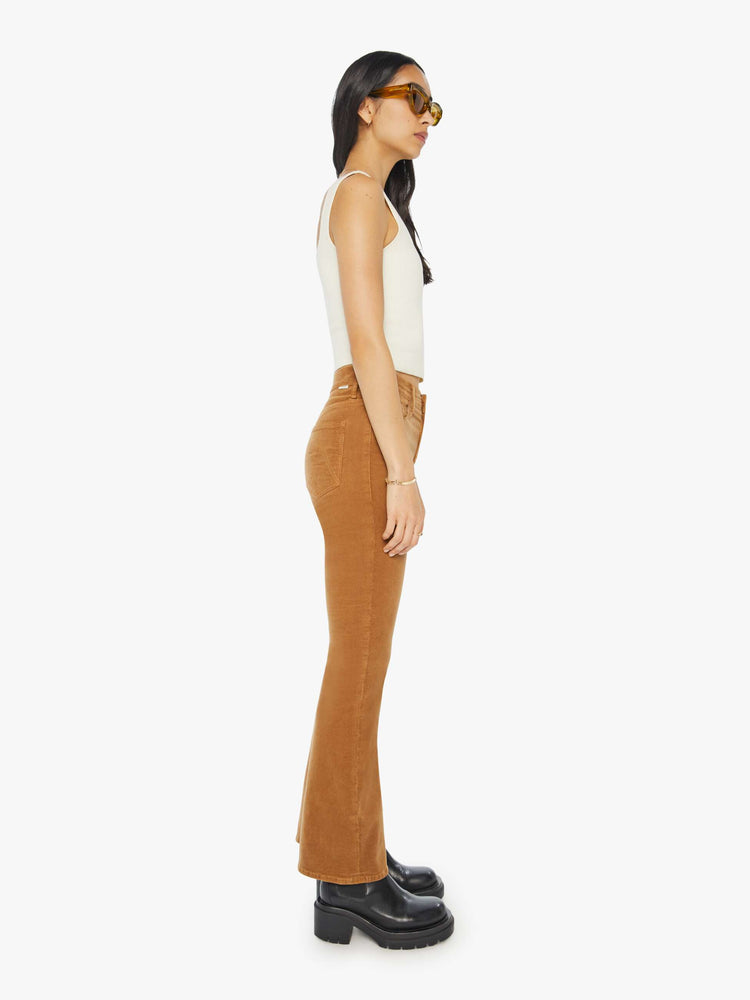 Side view of a woman in a mid rise with a 31-inch inseam and a clean hem in a golden orange corduroy.