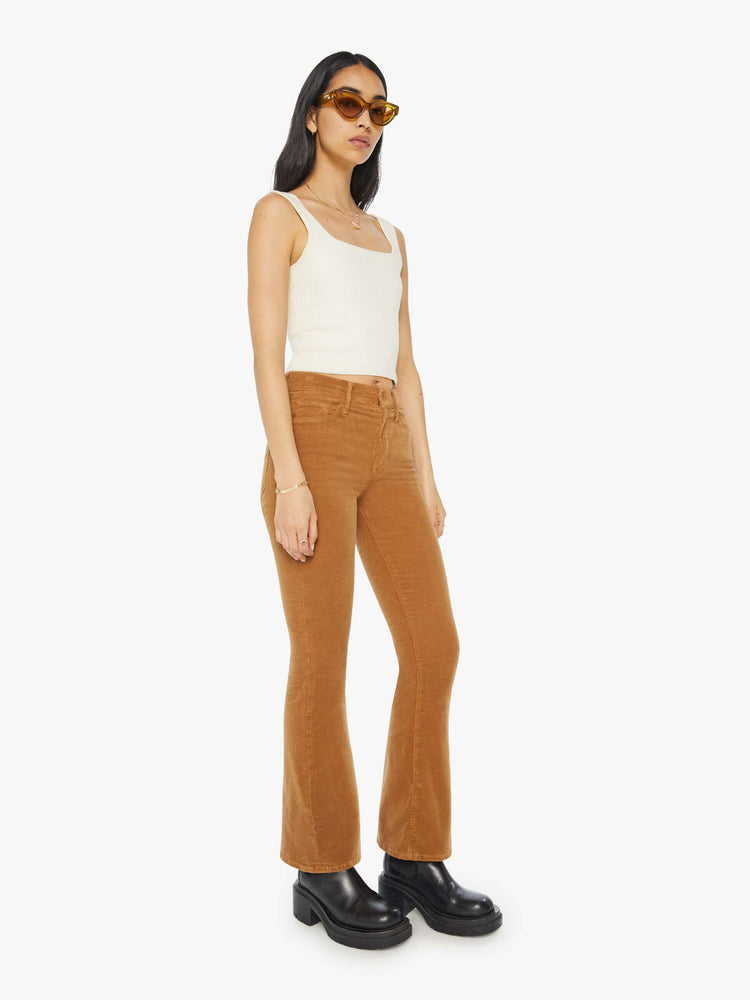 Side angle view of a woman in a mid rise with a 31-inch inseam and a clean hem in a golden orange corduroy.