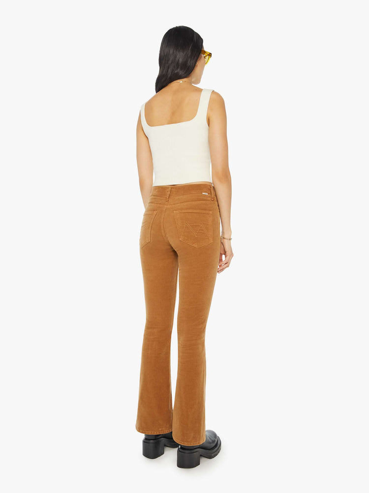 Back view of a woman in a mid rise with a 31-inch inseam and a clean hem in a golden orange corduroy.