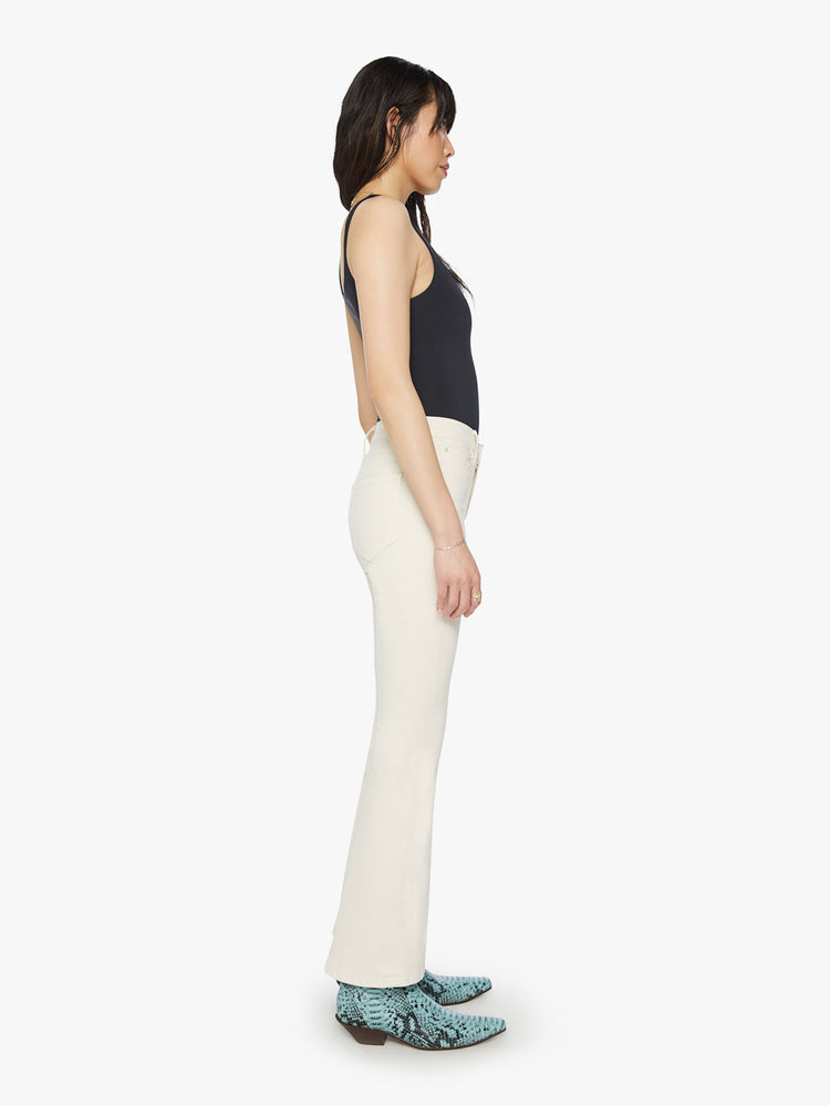 Side view of a woman midrise flare with a 31-inch inseam and a clean hem in an off white color.