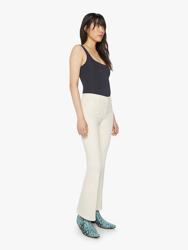 Side angle view of a woman midrise flare with a 31-inch inseam and a clean hem in an off white color.