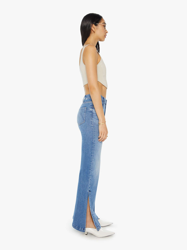 Side view of a woman in light blue high-rise wide-leg jeans with a long 32-inch inseam and a thick side-slit hem.