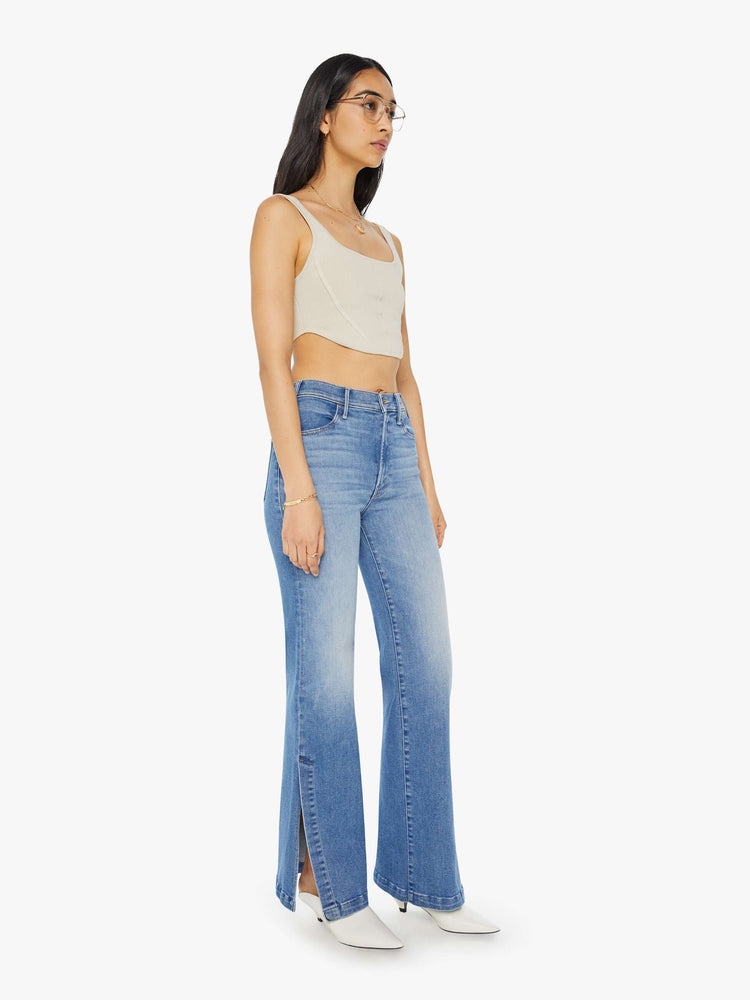 Angled front view of a woman in light blue high-rise wide-leg jeans with a long 32-inch inseam and a thick side-slit hem.