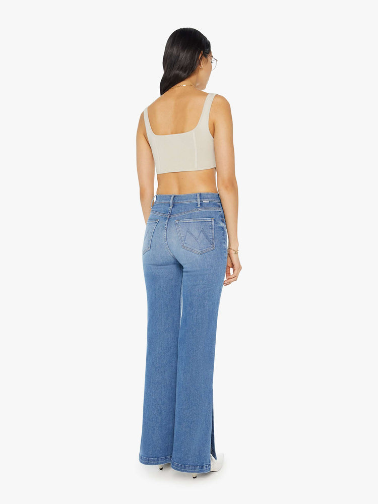 Back view of a woman in light blue high-rise wide-leg jeans with a long 32-inch inseam and a thick side-slit hem.