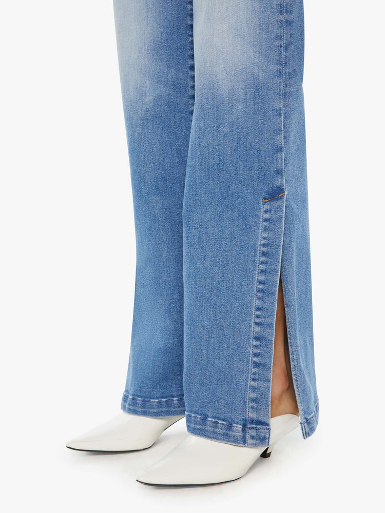 Detailed view of a woman in light blue high-rise wide-leg jeans with a long 32-inch inseam and a thick side-slit hem.