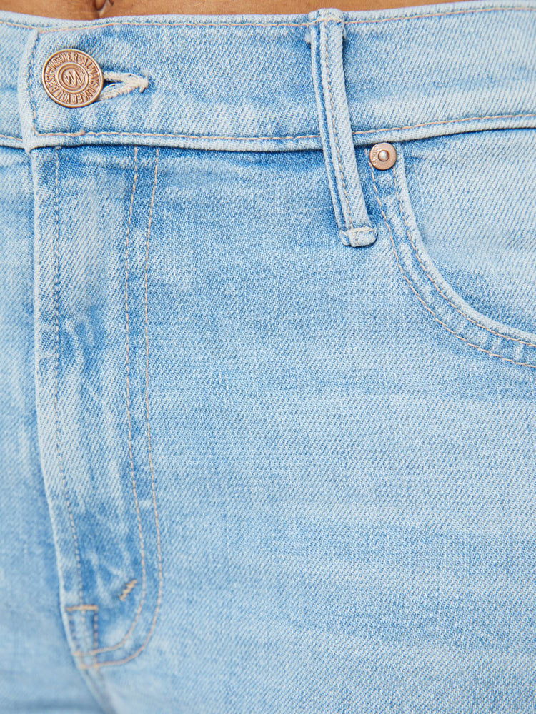 Swatch view of a woman in a light blue wash high-rise bootcut has an ankle-length inseam and a frayed hem. 