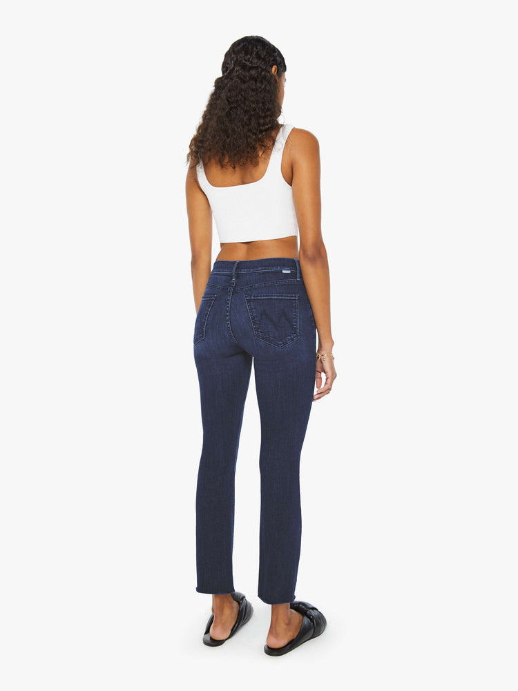 Back view of a woman in dark blue wash jeans with a mid-rise straight leg hits at the ankle with a clean hem.