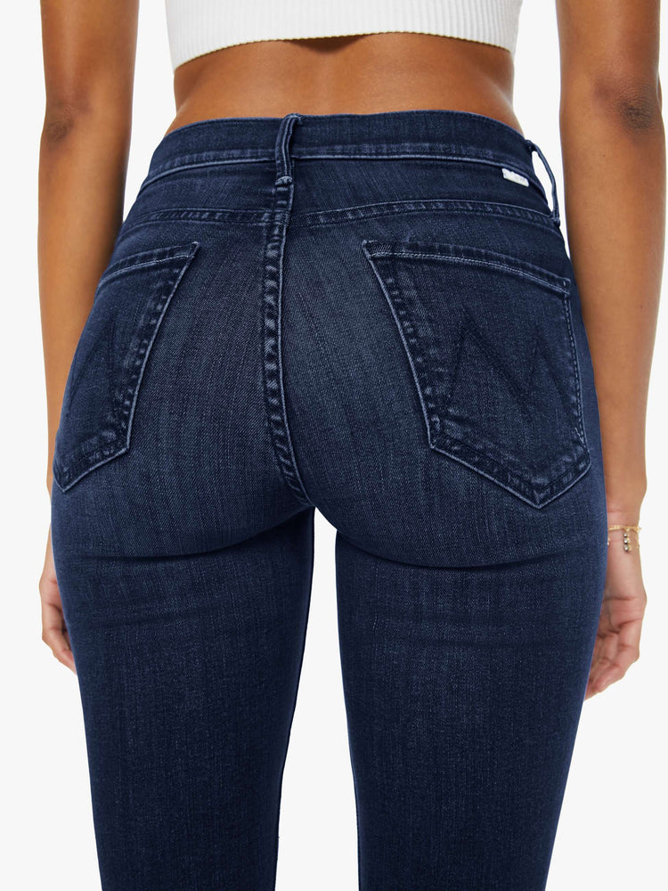 Back view of a woman in dark blue wash jeans with a mid-rise straight leg hits at the ankle with a clean hem.