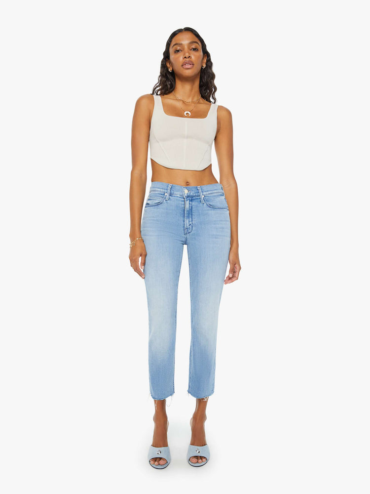 Front view of a womens light blue wash denim jean featuring a mid rise and a frayed crop hem.