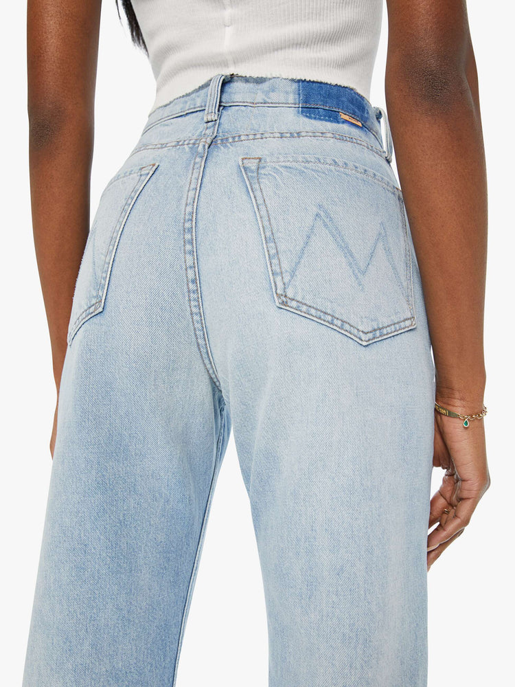 Close up view of a woman high-waisted  straight-leg jeans with a 30-inch inseam and a clean hem in a light blue denim.