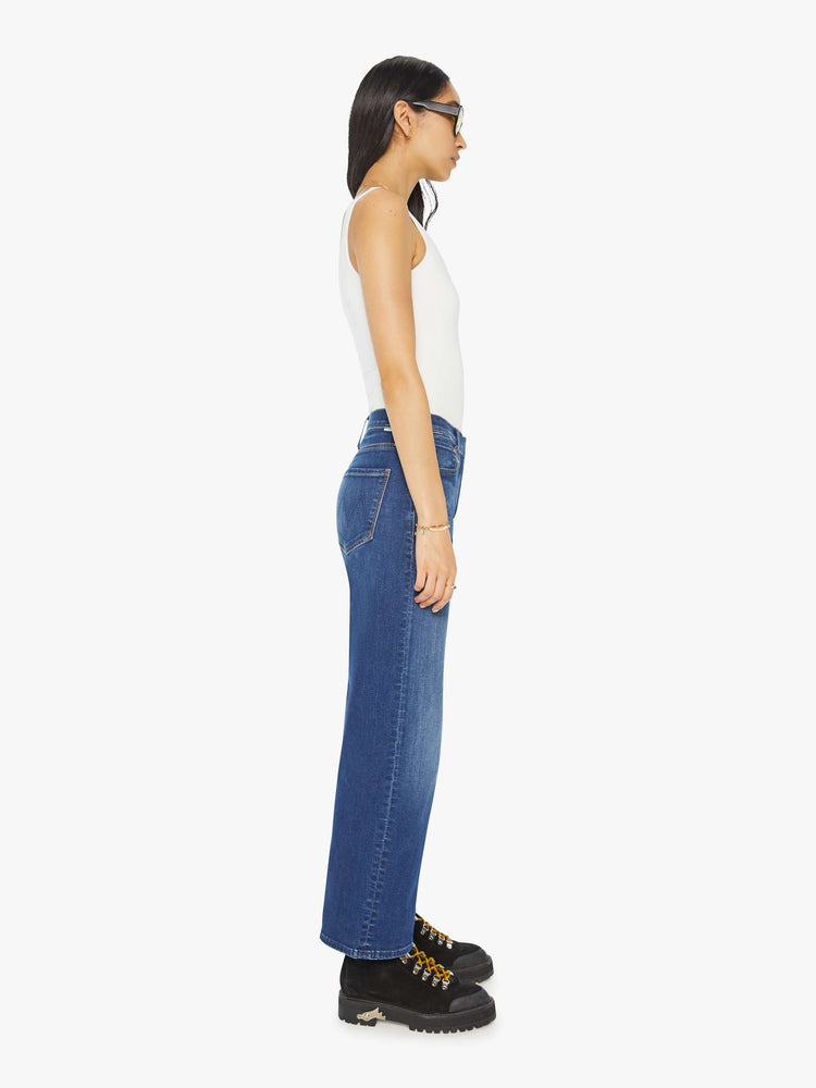 Side view of a woman in mid blue loose straight leg jean with an ankle-length inseam.