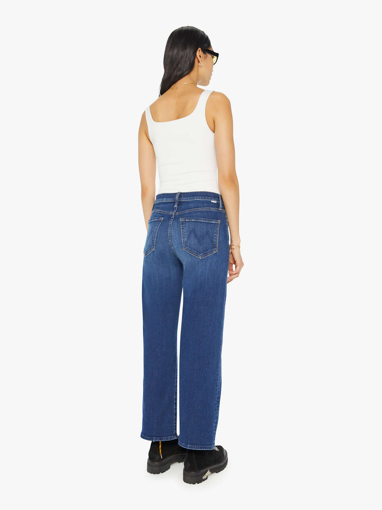 Back view of a woman in mid blue loose straight leg jean with an ankle-length inseam.