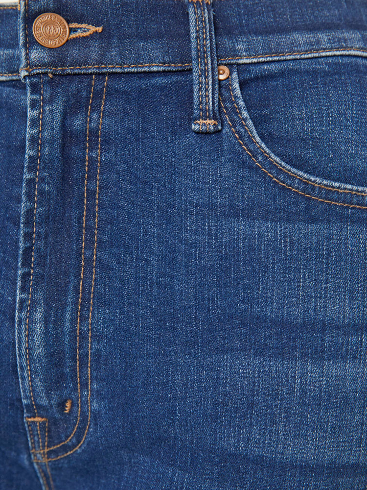 Detailed view of a woman in mid blue loose straight leg jean with an ankle-length inseam.