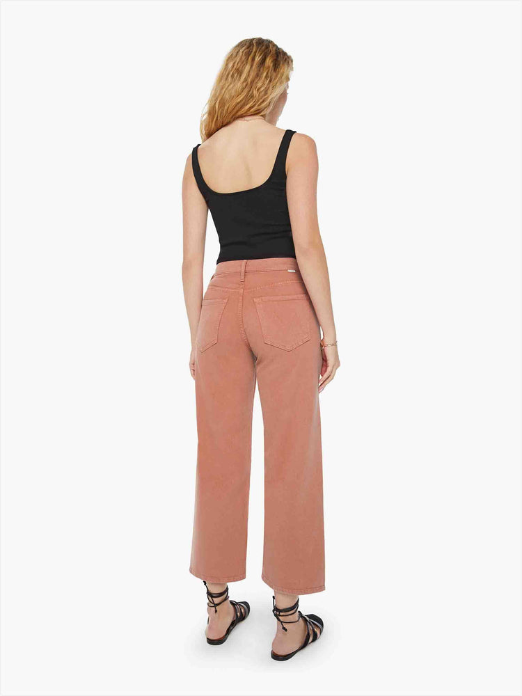 Back view of a woman in bright orange lower rise pants with a loose straight leg and a clean ankle-length inseam.