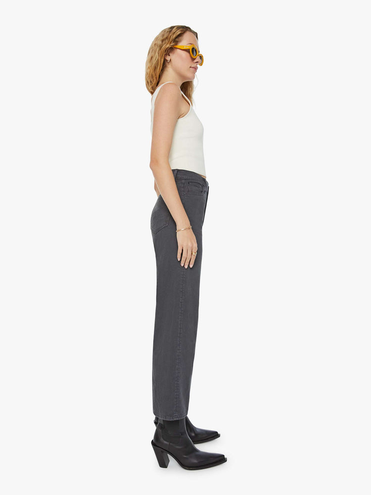 Side view of a woman in faded dark grey lower rise pants with a loose straight leg and a clean ankle-length inseam.