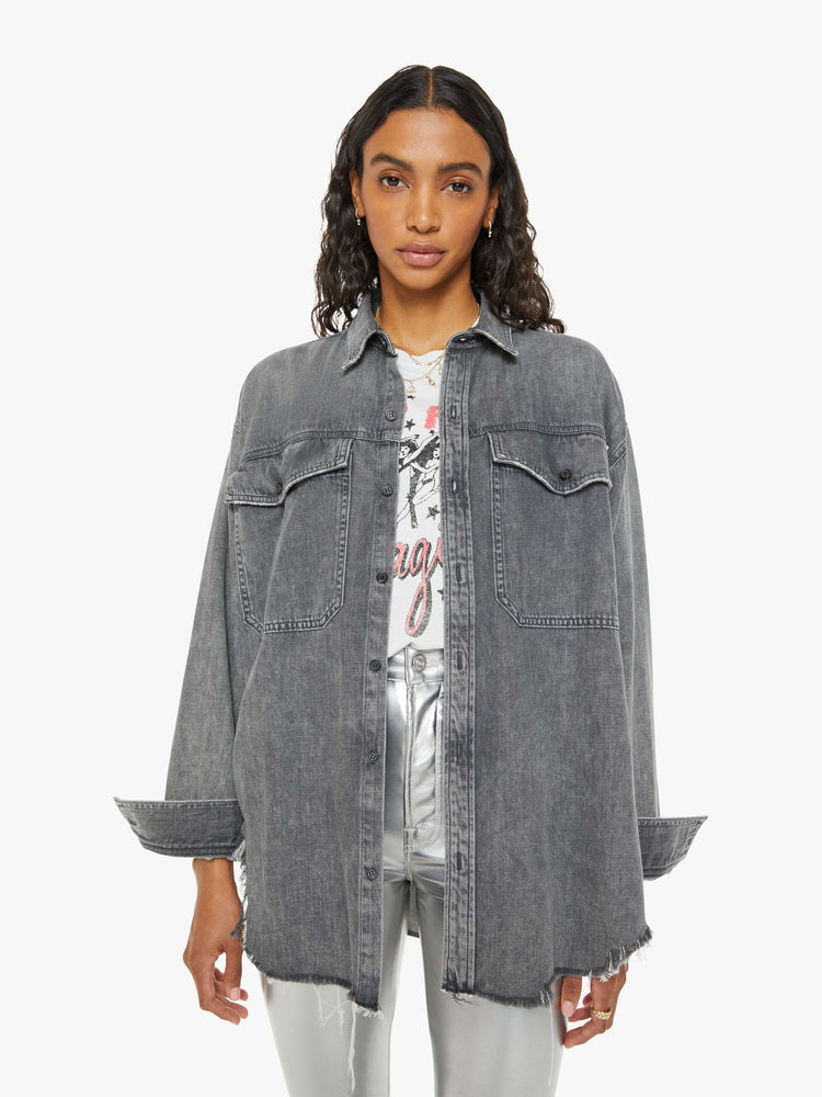 Front view of a woman  oversized button-up with drop shoulders, extra-large patch pockets and a frayed, curved hem in a dark grey.