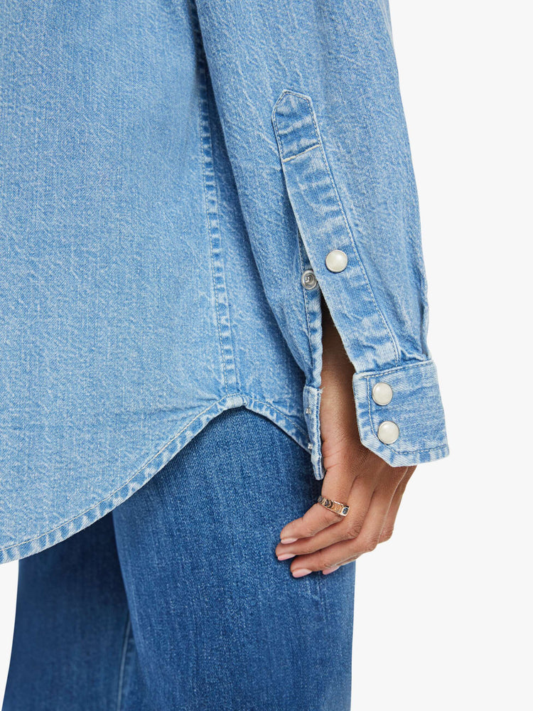 Swatch view of a woman in vintage blue wash  denim button-up with drop shoulders, front patch pockets, a Western-inspired yoke and a curved hem. 