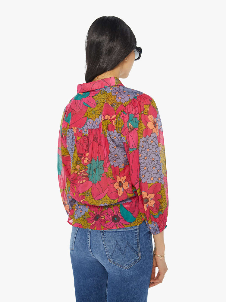 Back view of a woman in a collared V-neck blouse with 3/4-length balloon sleeves, a tied waist and ruffles throughout for a loose, flowy fit in a floral print.