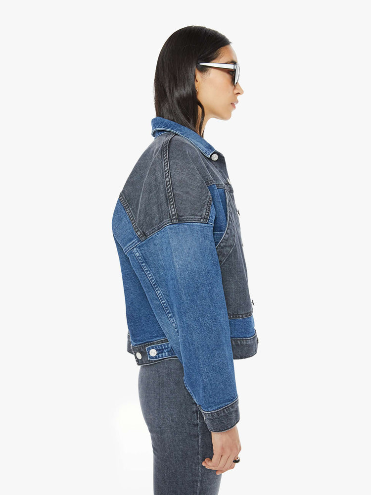 Side  view of a woman in med blue wash with black  denim jacket with drop shoulders, angled patch pockets on the chest and a classic fit. 