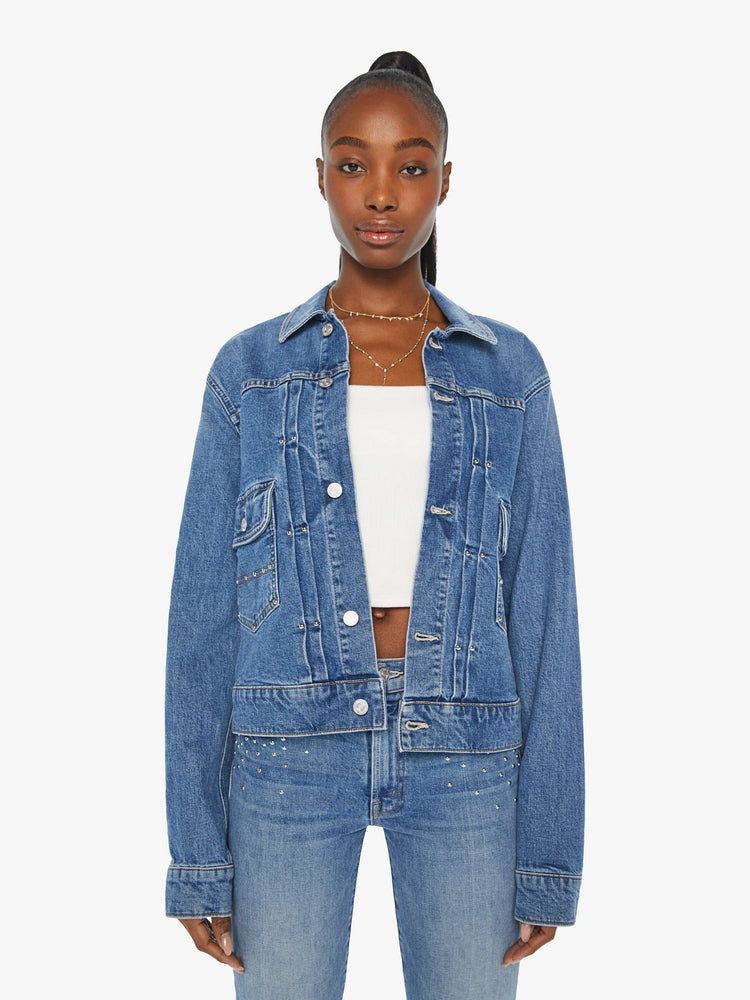 Front view of a woman denim jacket designed with drop shoulders, low patch pockets, adjustable tabs at the waist and pleated details down the front.