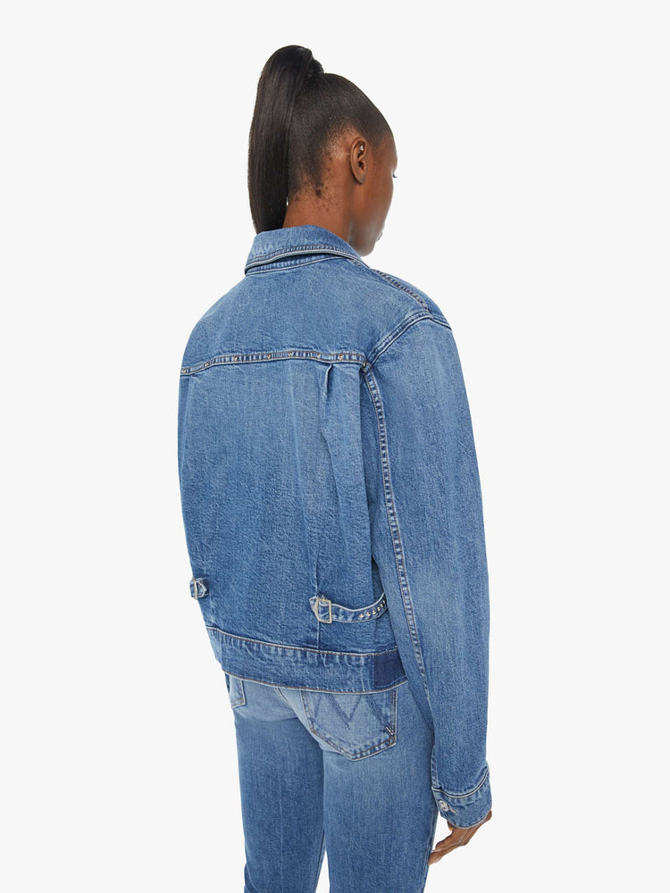 Back view of a woman denim jacket designed with drop shoulders, low patch pockets, adjustable tabs at the waist and pleated details down the front.