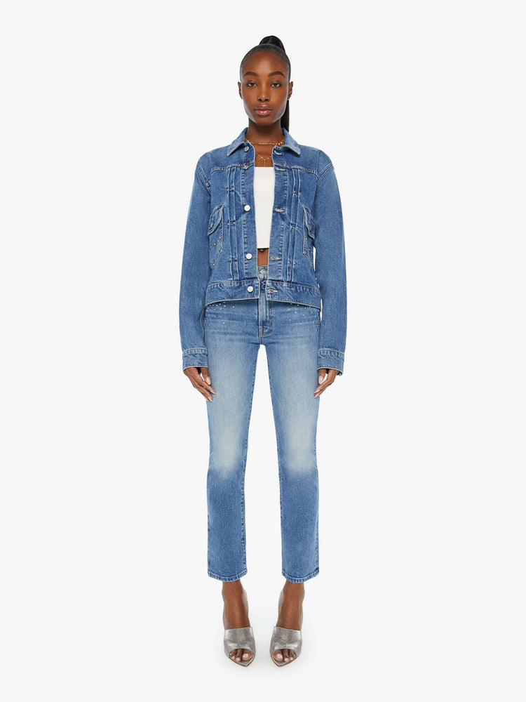 Full body view of a woman denim jacket designed with drop shoulders, low patch pockets, adjustable tabs at the waist and pleated details down the front.