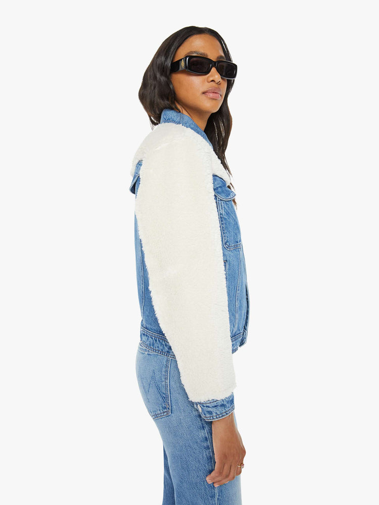 Side view of a mid blue classic denim jacket with faux sherpa with patch pockets and a boxy, slightly cropped fit.